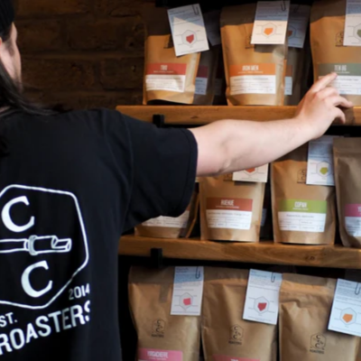 An image of a man picking a pack of coffee beans off a shelf