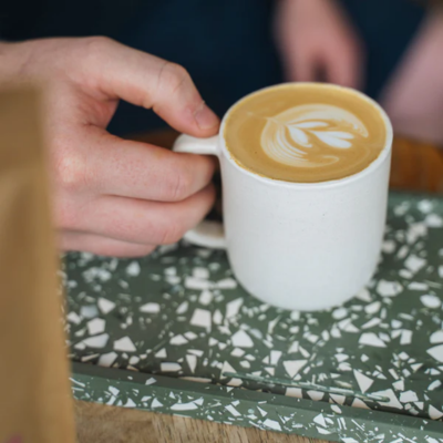 An image of someone holding a cup of coffee